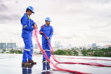 Electrical engineers are inspecting and installing a solar panels on the building rooftop.