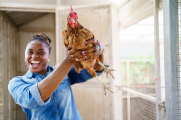 African - black woman holding a hen to camera and showing her beautiful smile.