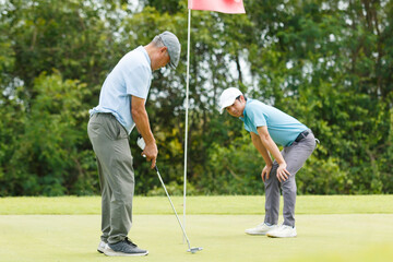 Asian man and elderly father are enjoy playing golf together with a good time.