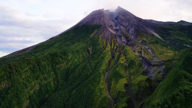 Scenic morning view of Mount Merapi, an active volcano in Central Java, Indonesia. showing volcanic ridges, tropical forest, and atmospheric sunrise light