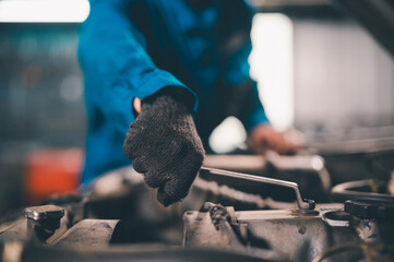 A person wearing a glove uses a wrench to tighten or loosen a bolt on an industrial machine or...