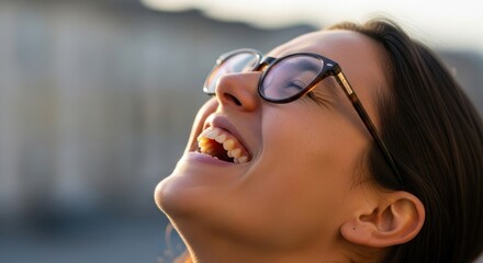 Joyful woman laughing outdoors in soft sunlight with blurred background scenery