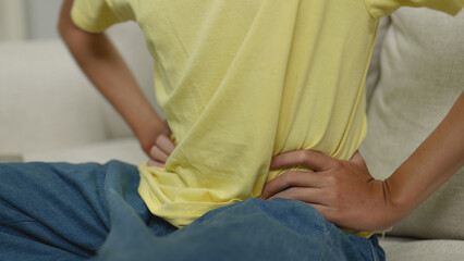 Asian man massaging his back to relieve pain.