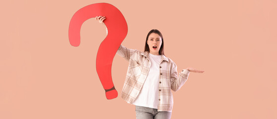 Young woman with big paper question mark on beige background