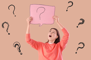 Shocked young woman holding speech bubble with question mark on beige background