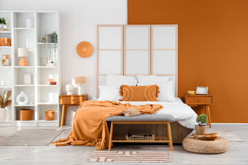 Interior of modern bedroom with big bed, folding screen and shelving unit