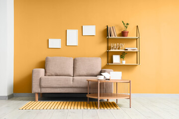 Wooden coffee table and grey sofa near green wall in interior of living room
