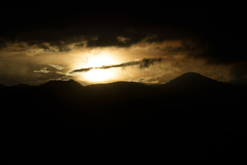 Dramatic sunset over mountain silhouette with dark stormy clouds offering ample copy space