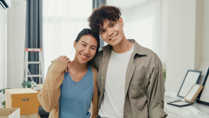 Young happy Asian sweet couple hugging each other smiling looking at camera show proud show off new...