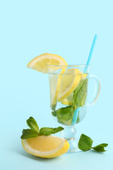 Glass of infused water with lemon and mint on blue background