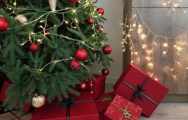 Christmas tree with glowing lights, gift boxes, red and golden balls in living room