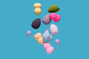 Flying different makeup sponges on blue background