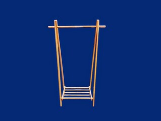 The dark blue background in the picture is a brown wooden clothes rack with four legs and a hanger that is a wooden rail with a wooden slot at the bottom used to put shoes or other things.