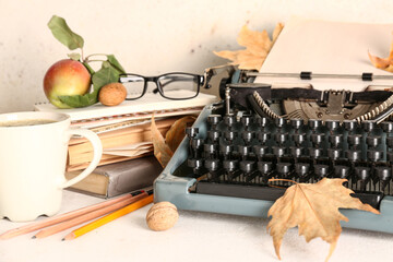 Vintage typewriter, cup of coffee and autumn leaves on white background