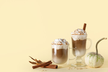 Glasses of tasty pumpkin latte with cinnamon and almond on yellow background