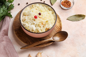 Bowl with delicious sauerkraut and different spices on pink background