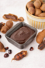 Bowl with tasty tamarind jam with fruits on white background