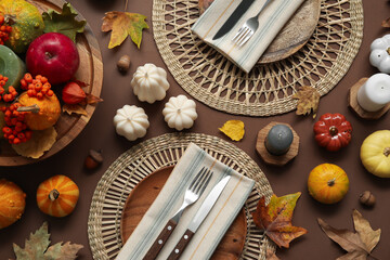 Stylish table setting with candles and autumn decor on brown background