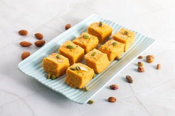 Soan Papdi is a flaky, sweet Indian dessert made with gram flour, sugar, ghee, and cardamom, known for its light, melt-in-mouth texture.
