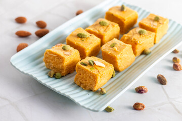 Soan Papdi is a flaky, sweet Indian dessert made with gram flour, sugar, ghee, and cardamom, known for its light, melt-in-mouth texture.
