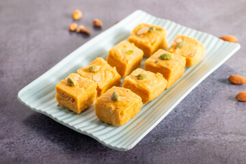 Soan Papdi is a flaky, sweet Indian dessert made with gram flour, sugar, ghee, and cardamom, known for its light, melt-in-mouth texture.
