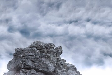 flat design illustration is showing layered jagged grey rock formation below dense cloud cover
