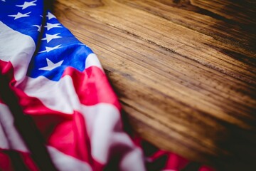 Folded American flag is resting on wooden tabletop in flat design and showing stars and stripes
