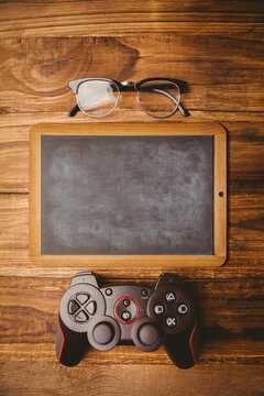 Fototapeta Chalkboard is lying on warm wood planks, in flat illustration with eyeglasses and game controller