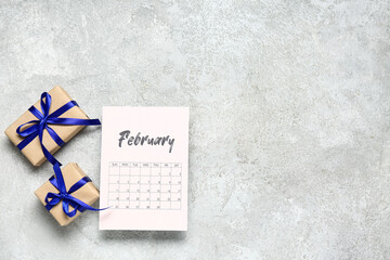 Paper calendar for February and gift boxes on grey background