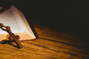 Bible kept on hardwood floor with rosary beads