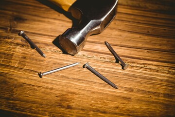 Hammer head with handle is being shown in flat design workshop scene, highlighting steel nails