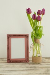 Photo frame and flower vase on table