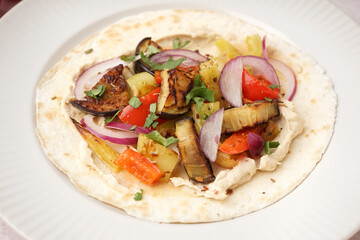 Tasty pita bread with grilled vegetables on plate, closeup
