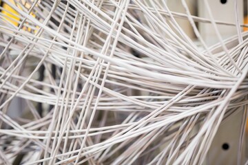 Showing tangled white network cables crossing flat design rack patch panel with metal guides
