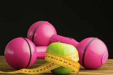 Pink dumbbells with green apple and measuring tape