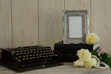 Photo frame, flowers and type writer on table