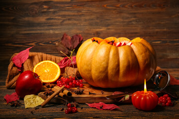 Beautiful composition with tasty mulled wine in pumpkin on wooden background