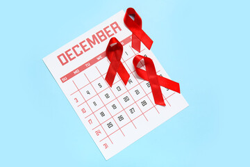 Red ribbons with calendar for December on blue background. AIDS Day concept