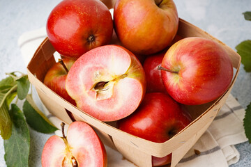 Basket with sweet pink apples and leaves on white background