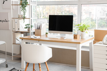 Obraz na płótnie Canvas Blank computer monitor with folders and plants near window in office