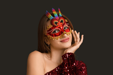 Beautiful young woman in red carnival mask on black background