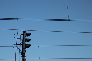 Railway signal post with electric wires against blue sky. Transport infrastructure, minimalism,...