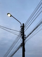 Illuminated street light and tangled electrical wires at dusk