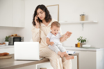 Working mother with her little baby talking by mobile phone in kitchen