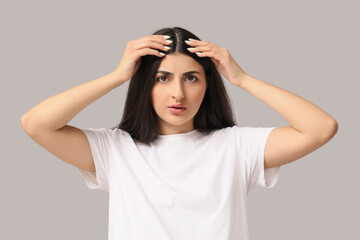 Fototapeta premium Young brunette woman with hair loss problem on grey background