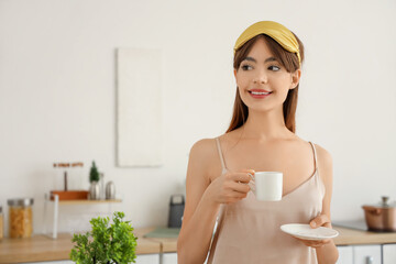 Beautiful young happy woman in pajamas with cup of coffee at home