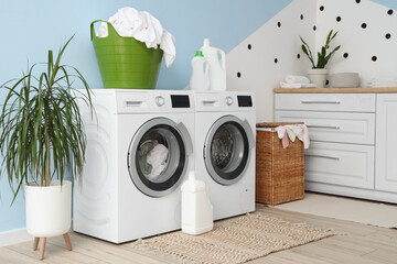 Interior of laundry room with washing machines, detergents and baskets