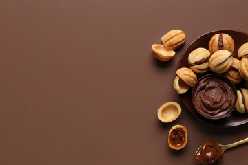 Bowl of sweet walnut shaped cookies with boiled condensed milk on brown background