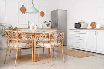 Interior of light kitchen with white counters, fridge and dining table