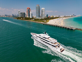 Yacht cruising near Miami skyline. Aerial view of boats on turquoise waters in Miami.